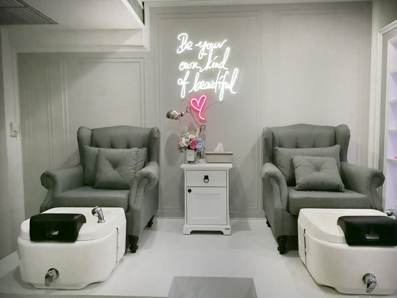 The two pedicure chairs under a neon sign at Lashley Studio